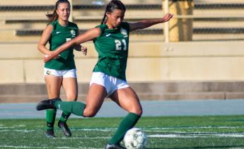 Women's soccer player kicking the ball