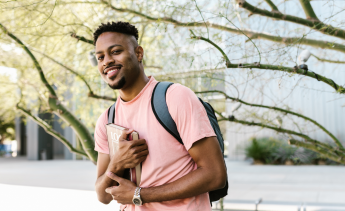 Black male student with backpack and books smiling