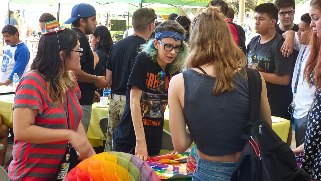 three student talking outside at a table 