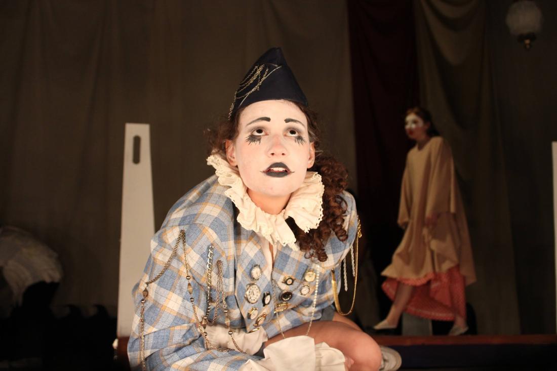 Image from LAVC Theatre & Dance departments production of Mr Burns - a post electric play. Actor in white face makeup looking up while lying on the edge of the stage.