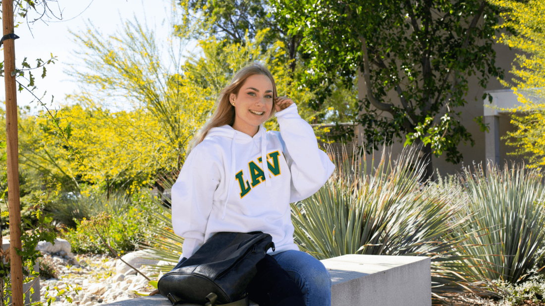 Blonde female student in LAVC sweatshirt sitting with backback